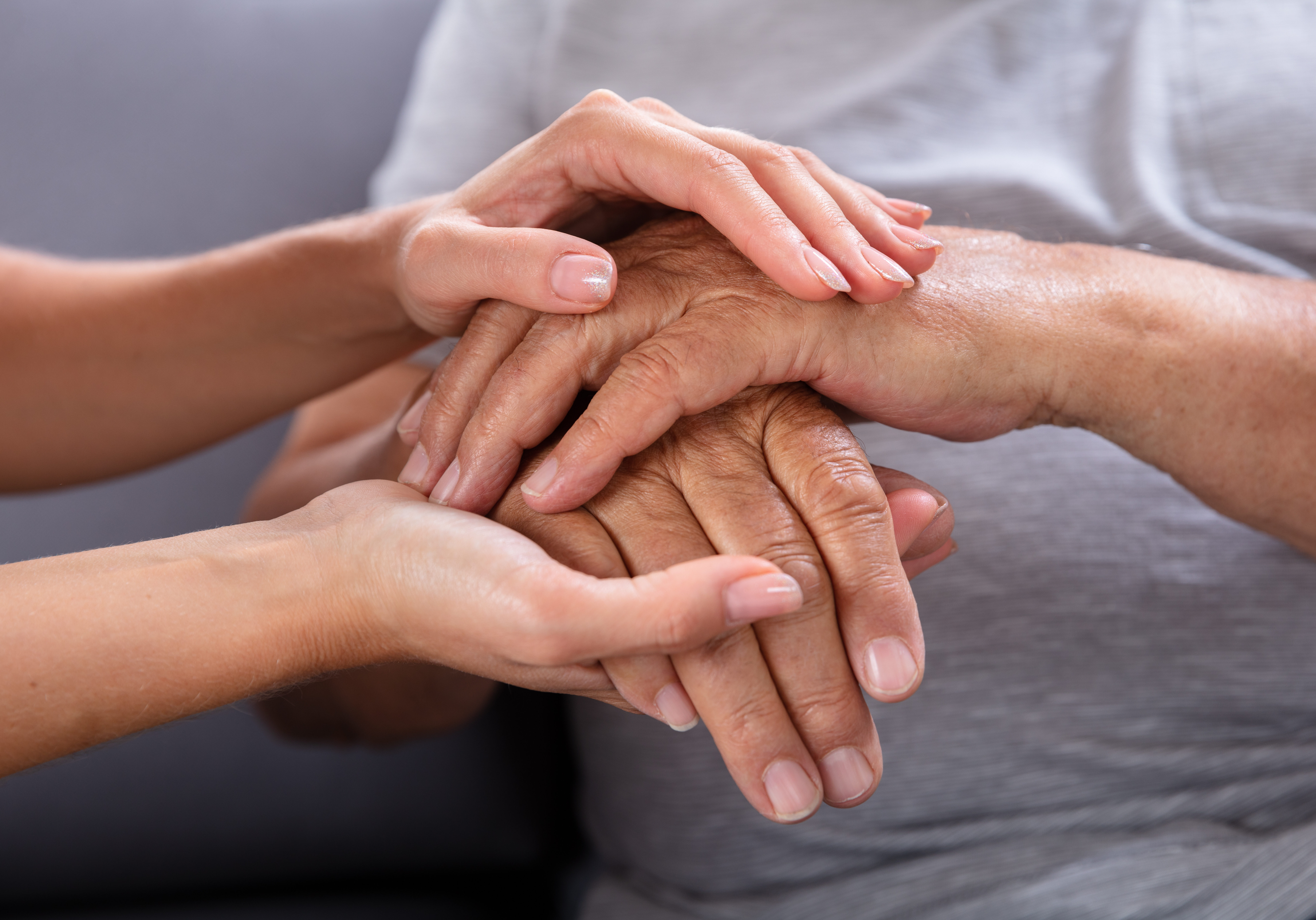 Close-up Of A Daughter Holding Her Elderly Father's Hand